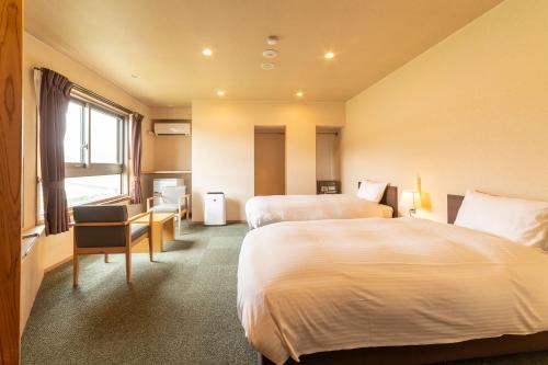 a hotel room with two beds and a window at Ooedo Onsen Monogatari Premium Kinosaki in Toyooka
