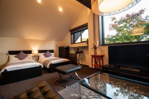 Cette chambre comprend deux lits et une télévision. dans l'établissement ユニテ蔵王ジョーニダ リゾート, à Yamagata