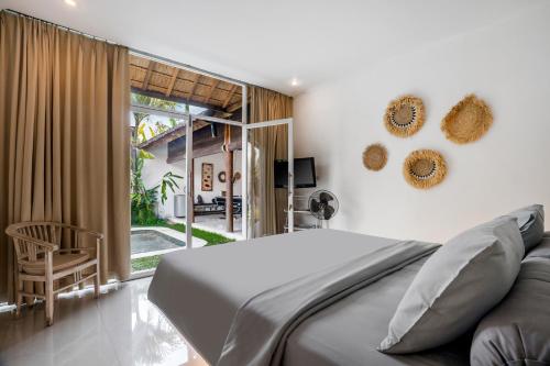 Villa Baik Baik by BaliSuperHost في سمينياك: غرفة نوم بسرير وباب زجاجي منزلق