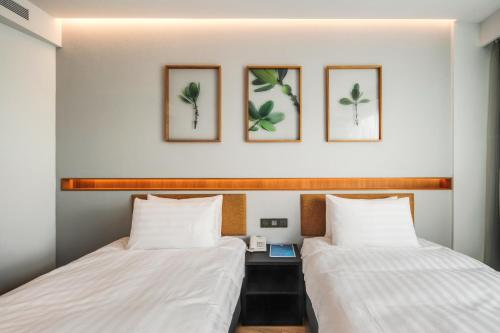 2 posti letto in una camera con 3 immagini a parete di Hayata Hotel a Città Vecchia di Hengchun