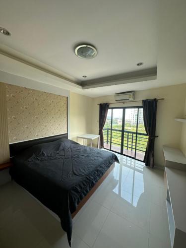 a bedroom with a bed and a large window at Prautamnak Grand Apartments in Pattaya South