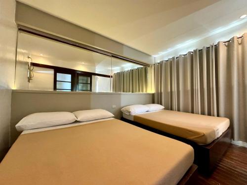 2 Betten in einem kleinen Zimmer mit Spiegel in der Unterkunft Espineli's in Balayan