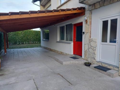 ein Haus mit einer roten Tür und einer Terrasse in der Unterkunft Skitnica Marilyn in Koprivnica
