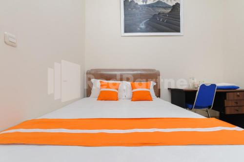 een oranje en wit bed met oranje kussens en een bureau bij Pondok Cimanggu Syariah Mitra RedDoorz in Bogor