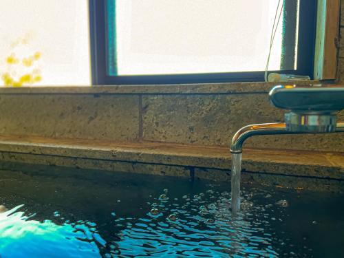 a water faucet in a pool of water at Izu Serenity Fuji-View Retreat with Private Onsen in Izu