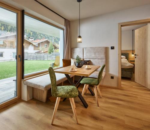 comedor con mesa, sillas y ventana en Apart Galeon, en Pettneu am Arlberg