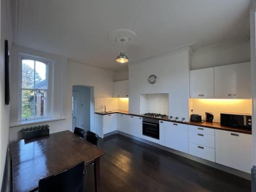 a large kitchen with white cabinets and a wooden table at Tranquil Retreat in Historic Chapelizod in Dublin