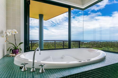 y baño con bañera y ventana grande. en A Perfect Stay - Above Byron en Byron Bay