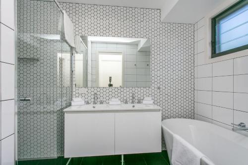 a bathroom with a sink and a tub and a mirror at A Perfect Stay - At the Beach in Suffolk Park