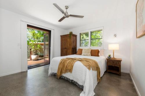 a white bedroom with a bed and a ceiling fan at Tallow Beach Retreat - welcoming pet-friendly unit in Suffolk Park