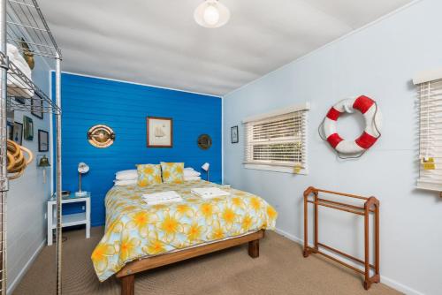 a bedroom with a bed with a blue wall at A Perfect Stay - Beachcombers Cottage in Suffolk Park