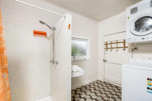 a bathroom with a shower and a washing machine at A Perfect Stay - Beachcombers Cottage in Suffolk Park