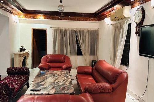 un soggiorno con mobili in pelle e TV a schermo piatto di Oriental Arcadia Elegant Apartment in Gulshan 2 a Dhaka