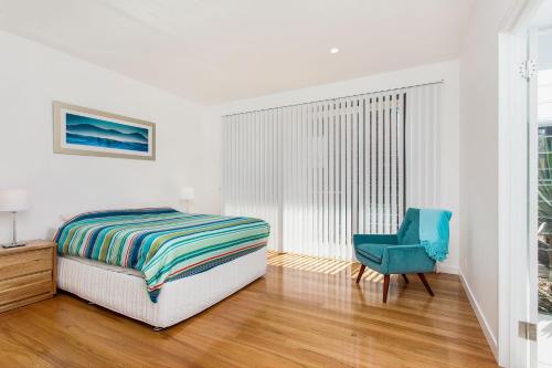 a bedroom with a bed and a blue chair at A Perfect Stay - Beachfront Tranquility in Suffolk Park