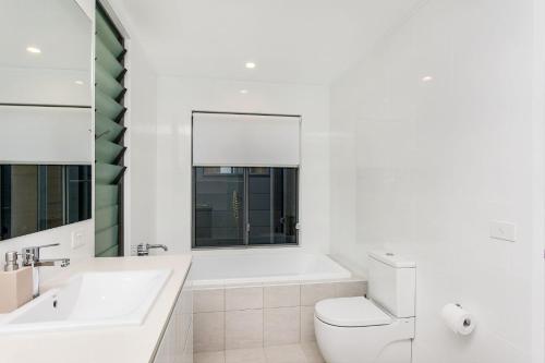 a white bathroom with a tub and a toilet and a sink at A Perfect Stay - Beachfront Tranquility in Suffolk Park
