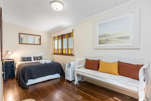 Dormitorio con cama, banco y pintura en A Perfect Stay - Byron Surf Cottage, en Byron Bay