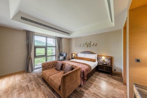 a bedroom with a bed and a couch and a window at Grand Cosmos Resort Ruisui Hualien in Ruisui