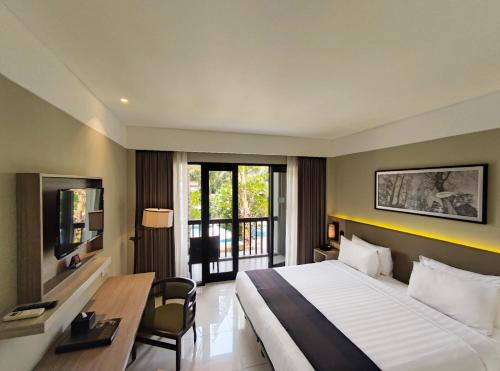 a hotel room with a large bed and a desk at eL Hotel Banyuwangi in Banyuwangi