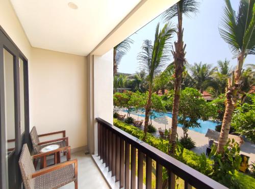 a balcony with a view of the pool and palm trees at eL Hotel Banyuwangi in Banyuwangi