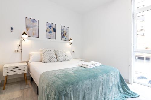 - une chambre blanche avec un lit et une couverture bleue dans l'établissement Estación RooMalaga by Bossh Apartments, à Malaga