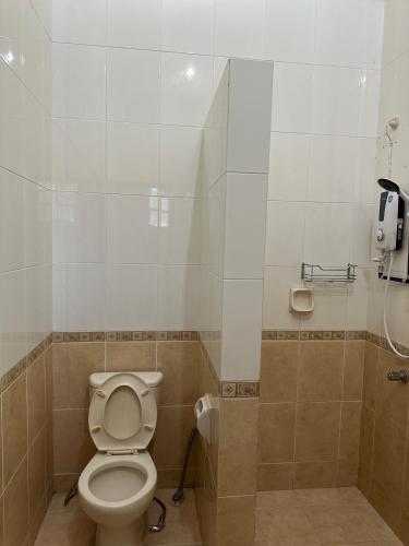 a bathroom with a toilet and a phone on the wall at Stutong Stay in Kuching