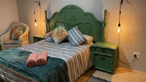 Un dormitorio con una cama verde con toallas. en Le Petit Guesthouse en Bloemfontein