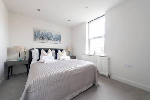 a white bedroom with a large bed and a window at Elevated Elegance: 1BR 1BA Flat in Wellmeadow Rd in London