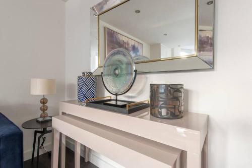 a table with a mirror and a fan on it at Elevated Elegance: 1BR 1BA Flat in Wellmeadow Rd in London