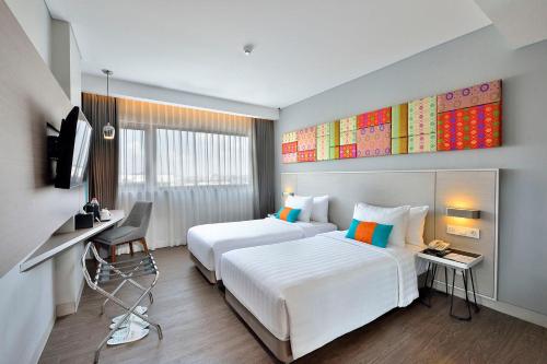 a hotel room with two beds and a desk at THE 1O1 Palembang Rajawali in Palembang