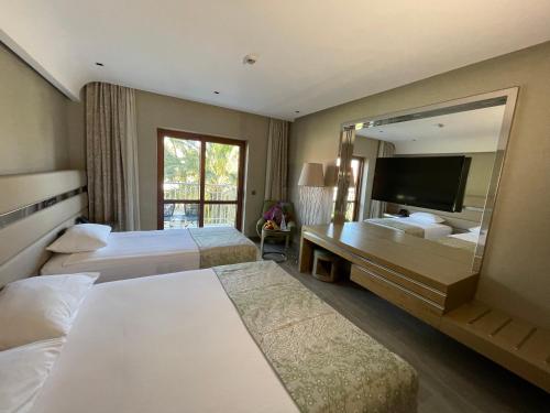 シダにあるCLUB GRAND AQUAのベッド2台と大きな鏡が備わるホテルルームです。