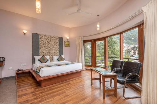 1 dormitorio con 1 cama, mesa y sillas en Spring Valley Resorts by DLS Hotels, en McLeod Ganj