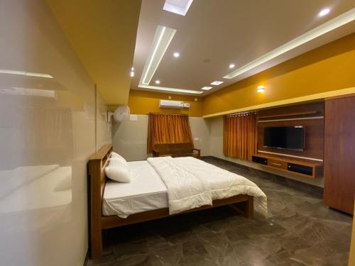 a bedroom with a bed and a flat screen tv at Shreesham Resort at Malpe Beach in Udupi
