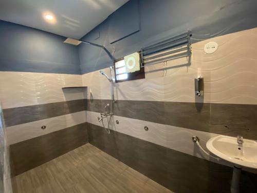 une salle de bain avec douche et lavabo dans l'établissement Shreesham Resort at Malpe Beach, à Udupi