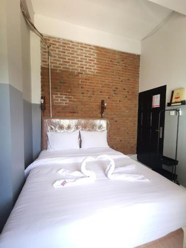 a large white bed in a room with a brick wall at 360 Homestay Padang in Kampungdurian