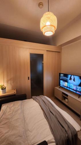 a bedroom with a bed and a flat screen tv at The New Villa at Sea Residences in Manila