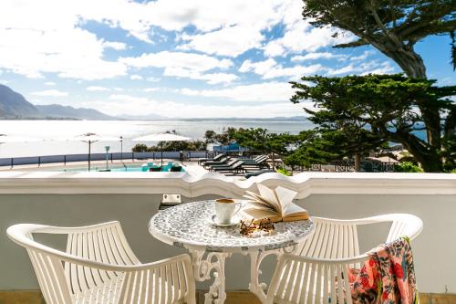 a table and chairs with a coffee cup and a book at Harbour House Hotel in Hermanus