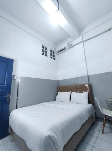 a bedroom with a large white bed and a blue door at 360 Homestay Padang in Kampungdurian