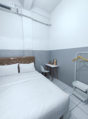 a bedroom with a white bed and a table at 360 Homestay Padang in Kampungdurian