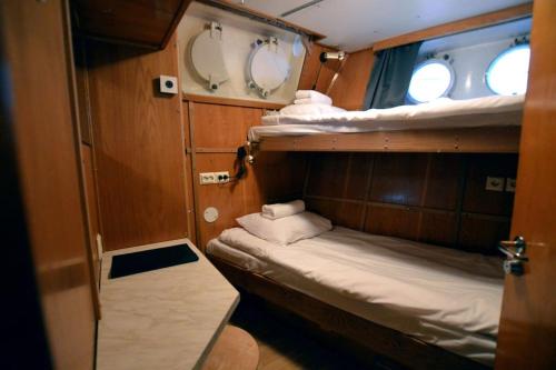 a small room with two bunk beds and two windows at Hotellilaiva Muikku/Hotel Boat Muikku in Helsinki