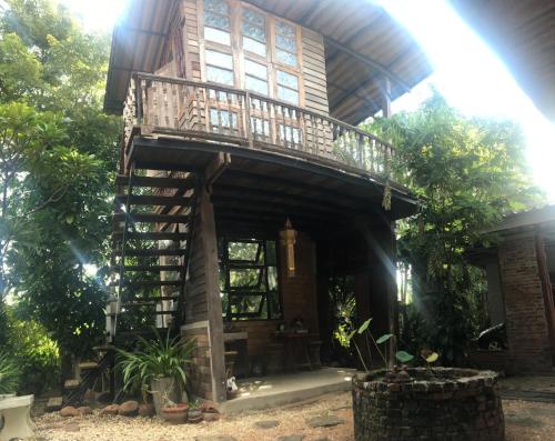una casa en el árbol con balcón en la parte superior en Baan Mali Lampang Homestay, en Lampang