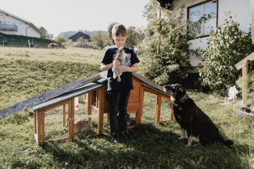 a young boy holding a dog in a dog house at Knollgut Ferienwohnung Buchberg in Goldegg
