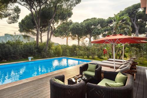 a patio with chairs and an umbrella next to a pool at Maxx Royal Belek Golf Resort in Belek