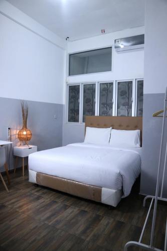 a bedroom with a large white bed and a window at 360 Homestay Padang in Kampungdurian