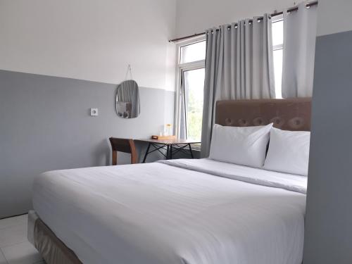 a bedroom with a large white bed with a window at 360 Homestay Padang in Kampungdurian