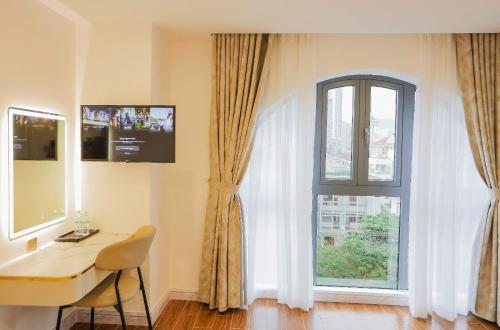 ニャチャンにあるKana Hotel Nha Trangのデスクと窓が備わる客室です。