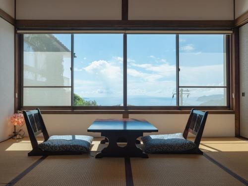 a table and two chairs in front of a large window at Atami Southern Wind　 熱海 南風楼(温泉付) in Atami