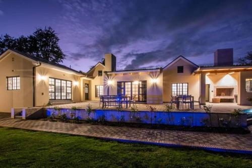 a large house with a patio at night at Eikenhof Estate in Brackenfell