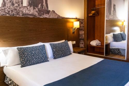 a bedroom with a bed with blue and white pillows at Hotel Adonis Plaza in Santa Cruz de Tenerife