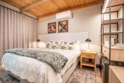 1 dormitorio con cama blanca y techo de madera en Eikenhof Estate, en Brackenfell