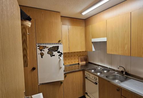 cocina con armarios de madera y nevera blanca en Waldrand Haus B 4. Stock, en Bellwald